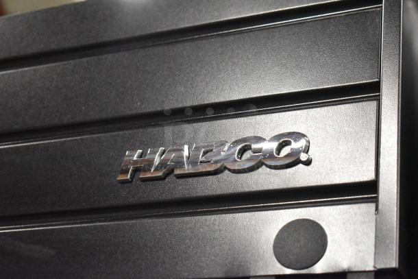 Close-up of Habco SE18 logo on a metal commercial single door reach-in cooler merchandiser in black.