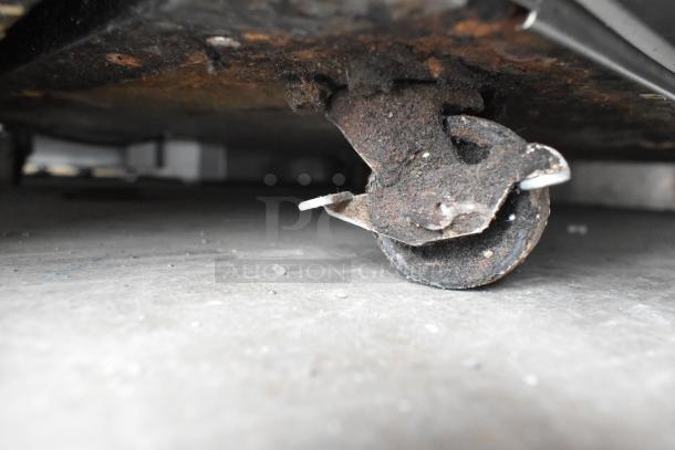 Close-up of a rusty caster wheel on a 2020 Delfield 406P-STAR2 stainless steel undercounter cooler, showing wear.