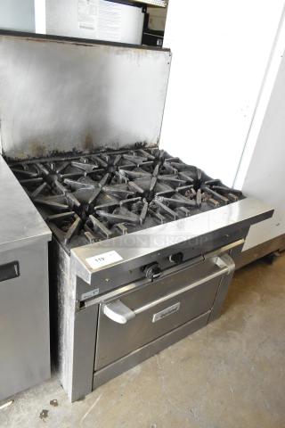 Garland Stainless Steel Commercial Gas 6 Burner Range with Oven, Backsplash. Used condition, visible wear, model label present.