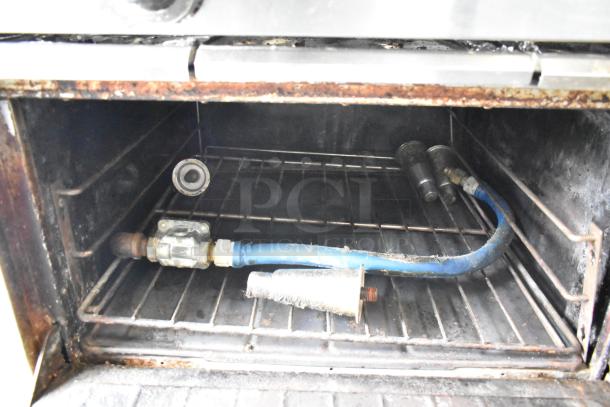 Oven interior of Garland stainless steel commercial gas range, showing racks and gas components. Used condition.