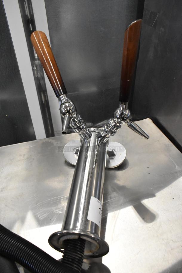 Stainless steel 2 tap beer tower with wooden handles, polished finish, mounted on a metal surface. Condition appears good.