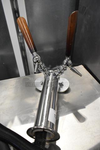 Stainless steel 2 tap beer tower with wooden handles, polished finish, mounted on a metal surface. Condition appears good.