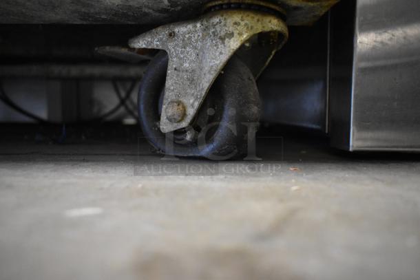 Atosa MCF8707 cooler caster wheel, showing wear and dirt, attached to stainless steel base. Suitable for commercial kitchens.