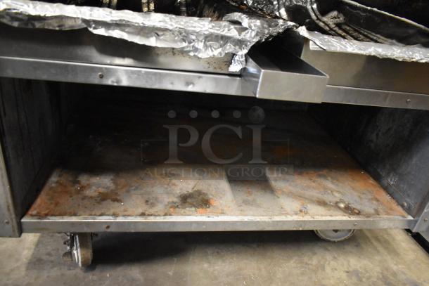 MagiKitch'n stainless steel commercial natural gas charbroiler grill, visible shelves, wheels for mobility, used condition.