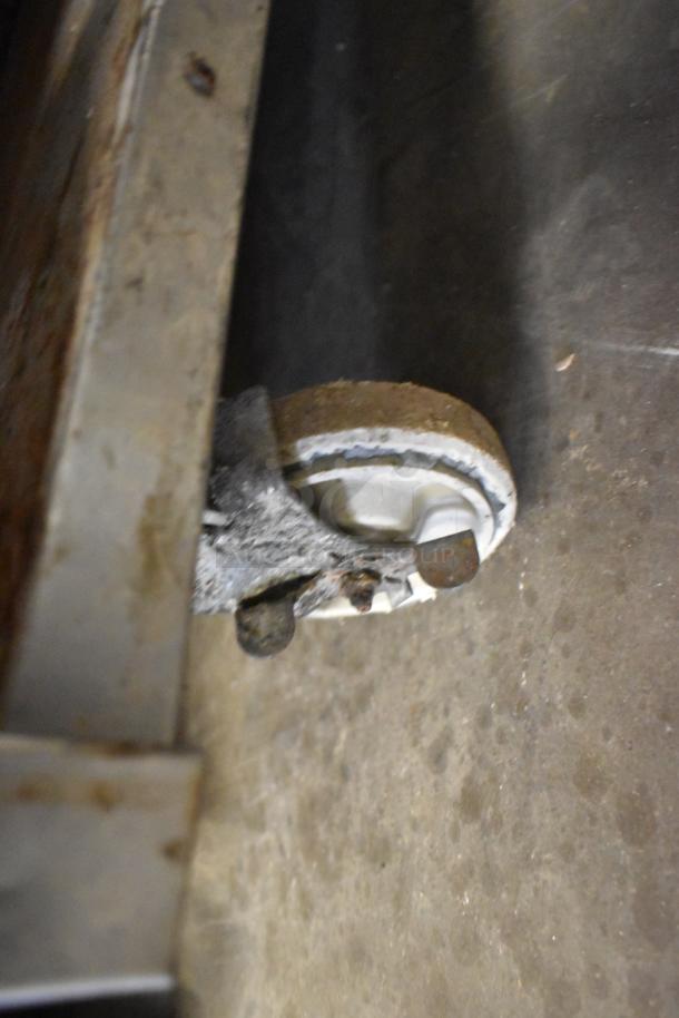 MagiKitch'n commercial charbroiler grill caster wheel, showing wear and rust. Stainless steel construction detail visible.