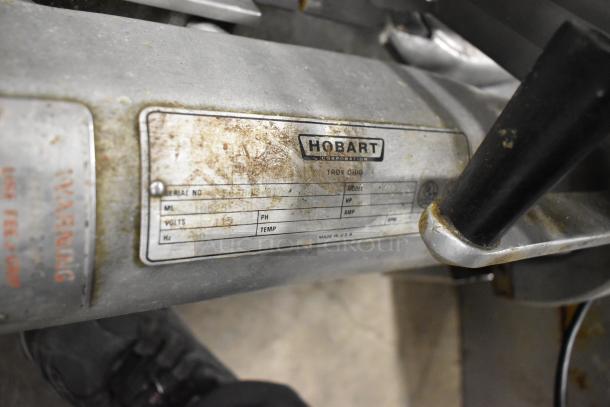 Hobart 1712 commercial meat slicer, metal construction, 115 volts, 1 phase. Label shows make, model, and voltage details.