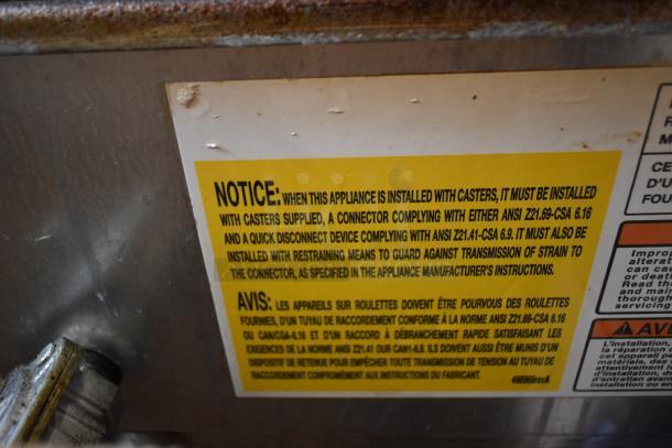 Vulcan VACB25-101 stainless steel grill, commercial natural gas, 68,000 BTU, on equipment stand. Safety warning label visible.