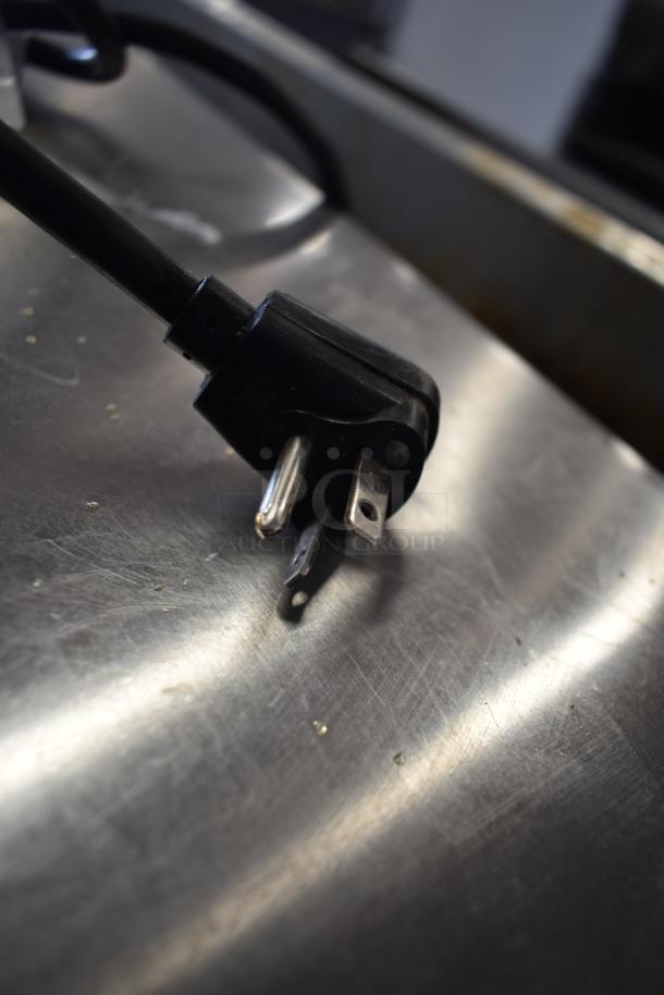 Power plug of a 2025 Solwave SWAHD12 stainless steel commercial microwave, 120 volts, shown on a metal surface.