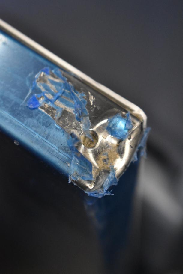 Close-up of a damaged corner on a Hoshizaki AM-50BAK ice machine. Visible scratches and peeling protective film.