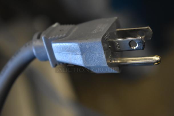 Close-up of a three-prong plug attached to the 2017 Amana RCS10TS stainless steel commercial microwave.