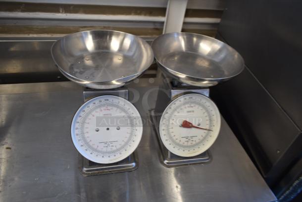 Two Cardinal Detecto SCS30 30 lb. solar power hanging scales with white dials and metal trays, in good condition.