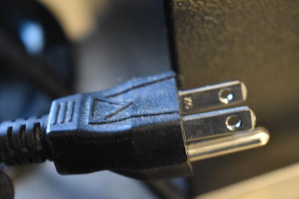 Close-up view of a power plug for a Bunn VPR coffee brewer, showing standard U.S. configuration and black casing.