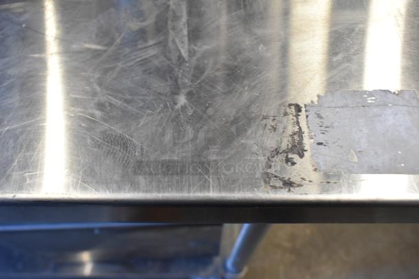 Close-up image of a scratched metal surface with remnants of a sticker or label, showing signs of wear and use.