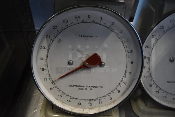 Three metal countertop scales with a white dial, red pointer, and 25 lb capacity. Some wear visible, marked "Temperature Compensated."