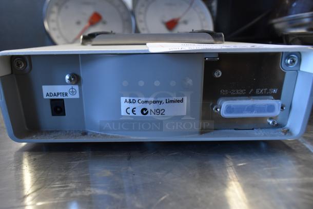 A&D GF-300P metal countertop scale, back view showing adapter port and labels with branding and CE mark, slight wear visible.