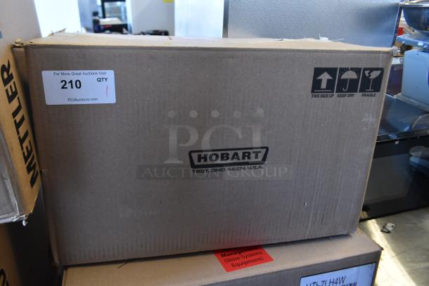 2017 Hobart HTi-7LH26 metal commercial food portioning scale in box. Labels indicate item and handling instructions.
