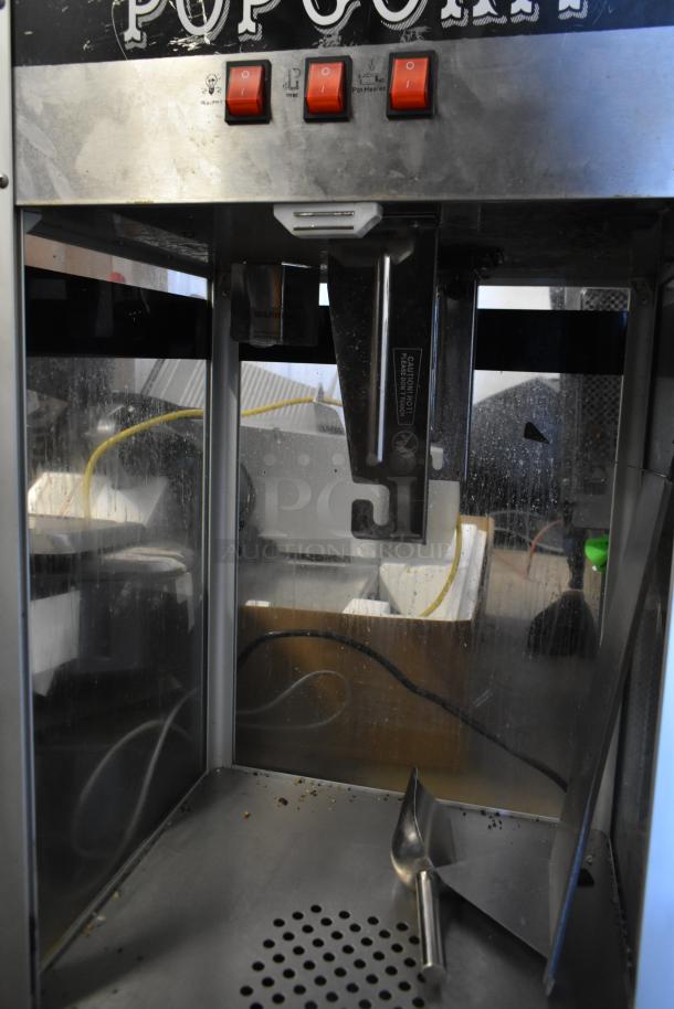 Metal commercial countertop popcorn maker with red control switches. 115 volts, 1 phase, used condition with interior scoop.