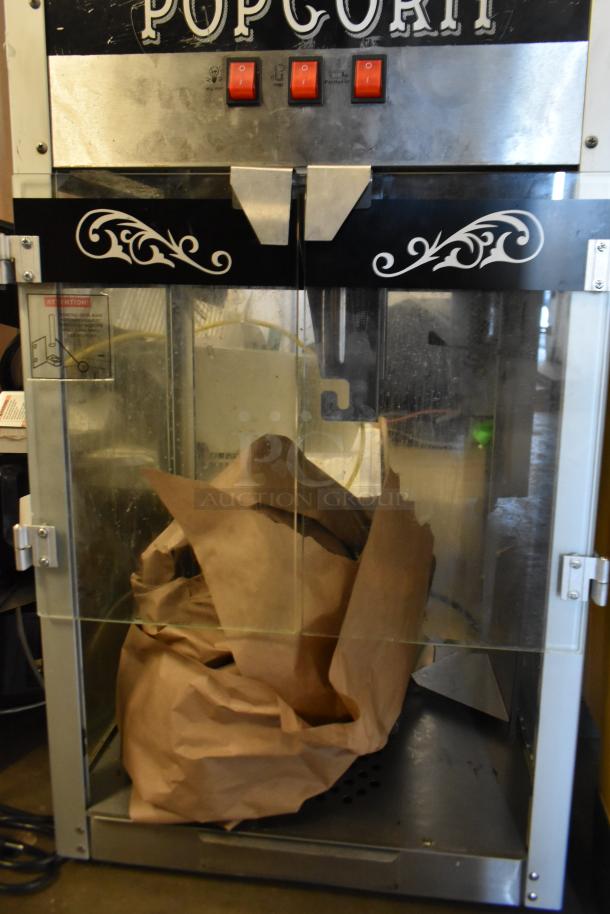 Metal commercial popcorn maker merchandiser with glass doors and decorative details. Rated 115 volts, 1 phase. Used condition.