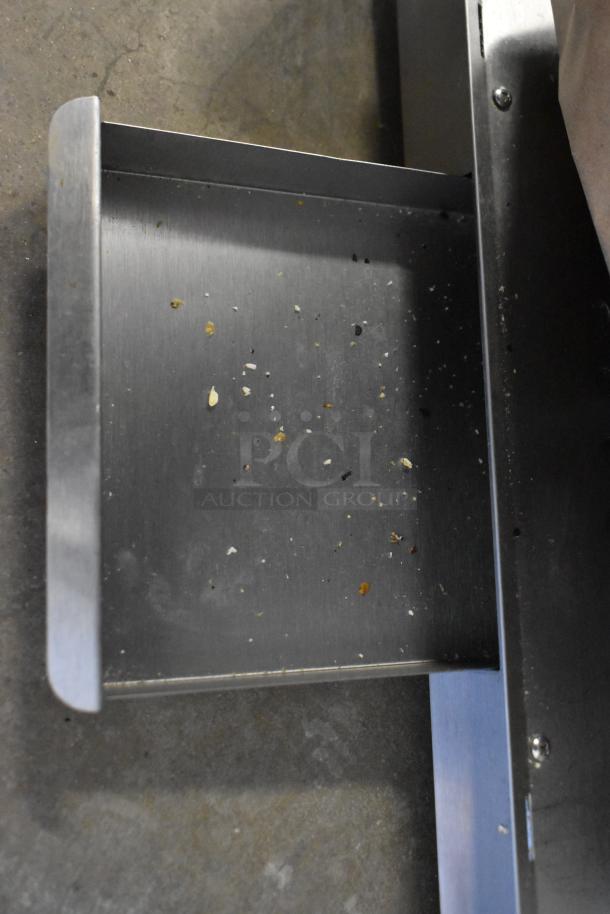 Metal commercial countertop popcorn maker with visible metal tray. Operates at 115 volts, 1 phase. Shows minor debris.