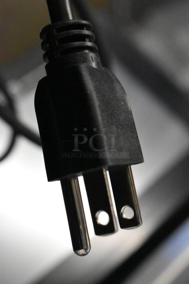Close-up of a pronged plug attached to a Hobart HTi-LH26 food portioning scale, 120/208-240V, 1 phase.
