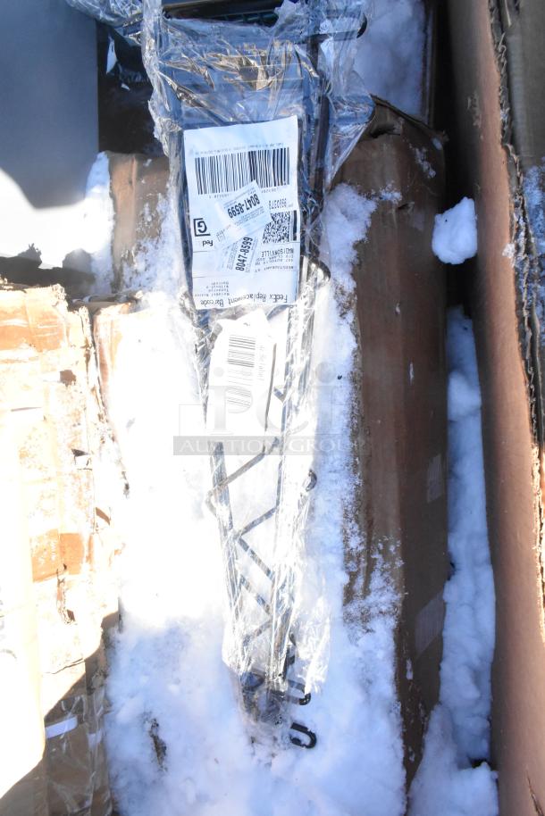 Clear-wrapped item labeled with shipping barcodes, resting in snowy cardboard box. Part of a scratch and dent auction lot.