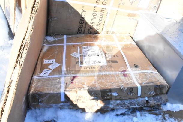 Cardboard boxes of brand new "scratch and dent" kitchen items including fryer and chafer, wrapped and labeled on snow.