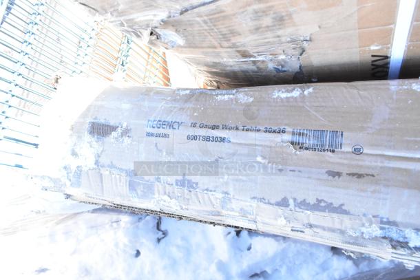 Cardboard box labeled "Regency 16 Gauge Work Table 30x36" with snow and damage visible.