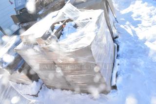 Shrink-wrapped pallet of 9 brand new scratch and dent items, including a tabletop and vinyl padded seats, in snowy setting.