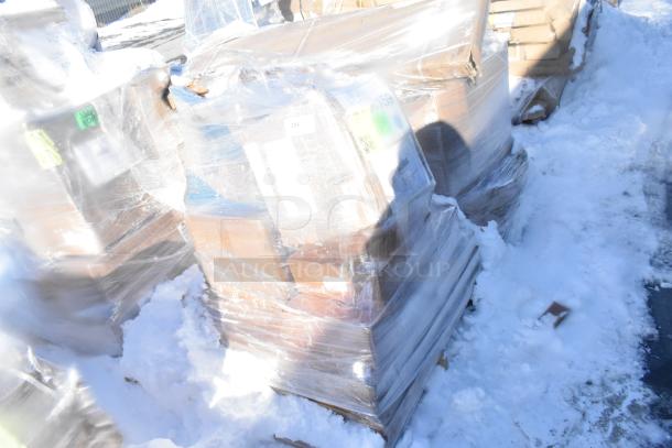 Pallet of assorted scratch and dent items, including tabletops, wok, toilet dispenser, wrapped in plastic, snowy background.