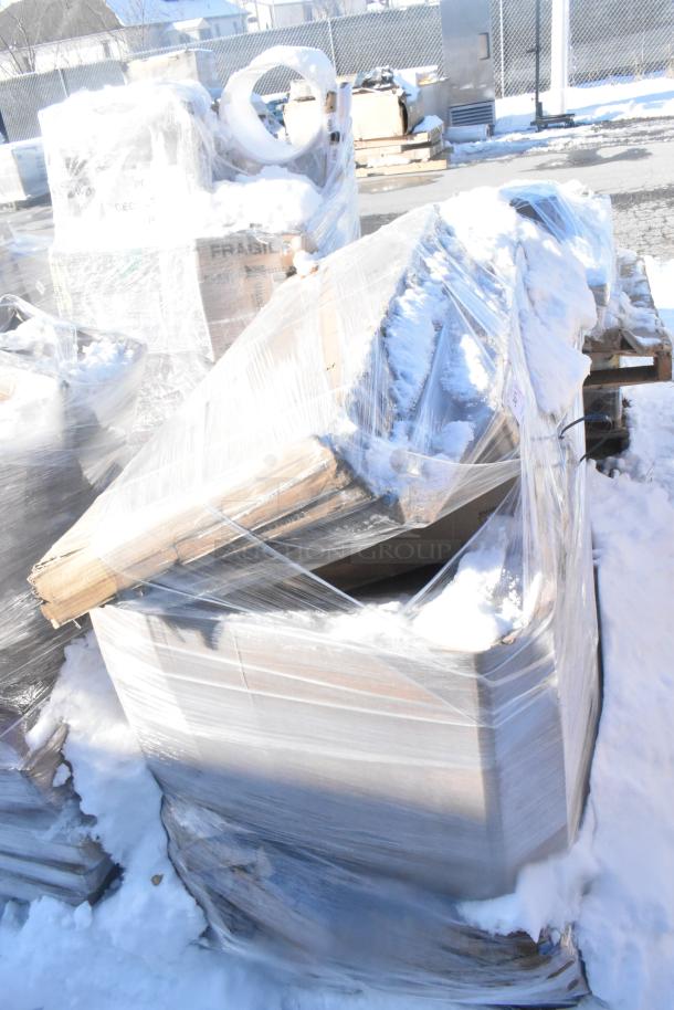 Five brand new scratch and dent items, including a sink and overshelves, wrapped in plastic on a snowy pallet.