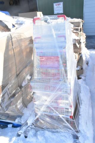 Pallet of four metal shopping carts, brand new, shrink-wrapped, some scratch and dent, on snowy ground, auction lot.