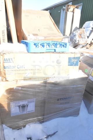 Stack of boxes labeled "Janitor Cart" and "Town" in original packaging with visible scratch and dent wear. Snow-covered.