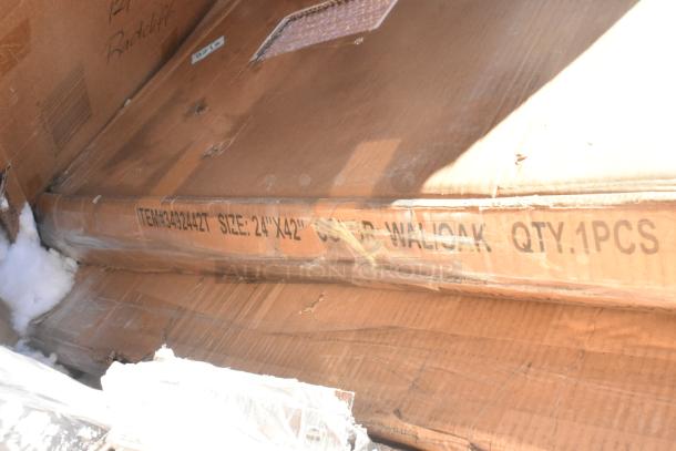 Cardboard box containing a new item labeled "ITEM#3492442T SIZE: 24"x42" COLOR: WALOAK QTY.1PCS," with visible packaging wear.