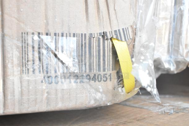 Cardboard packaging with visible scratches and dents, showing a barcode and yellow strap. Contains new items including Bakers Lane Ingredient Bin, Regency Table, and Pan Racks.