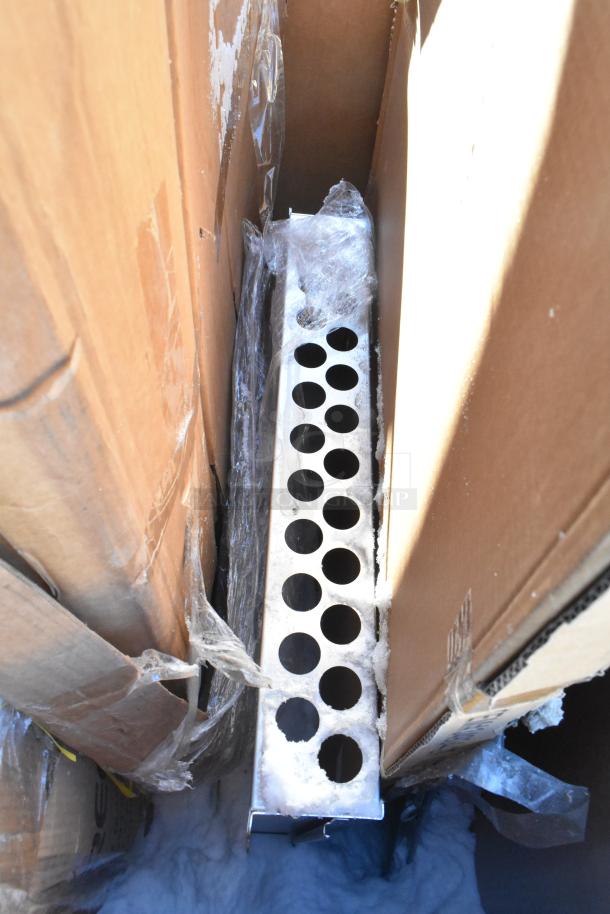 Seven new scratch and dent items, including a Bakers Lane Ingredient Bin and Regency Pan Racks, wrapped in plastic.