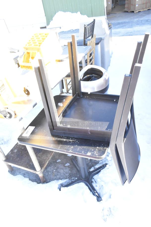 Outdoor image of a black table and two chairs stacked on snow. Some scratches visible. Tag marked "257."