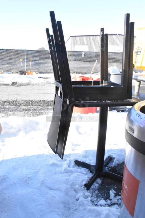 Stacked black table and two chairs, metal base, snow background. Suitable for outdoor or indoor use.