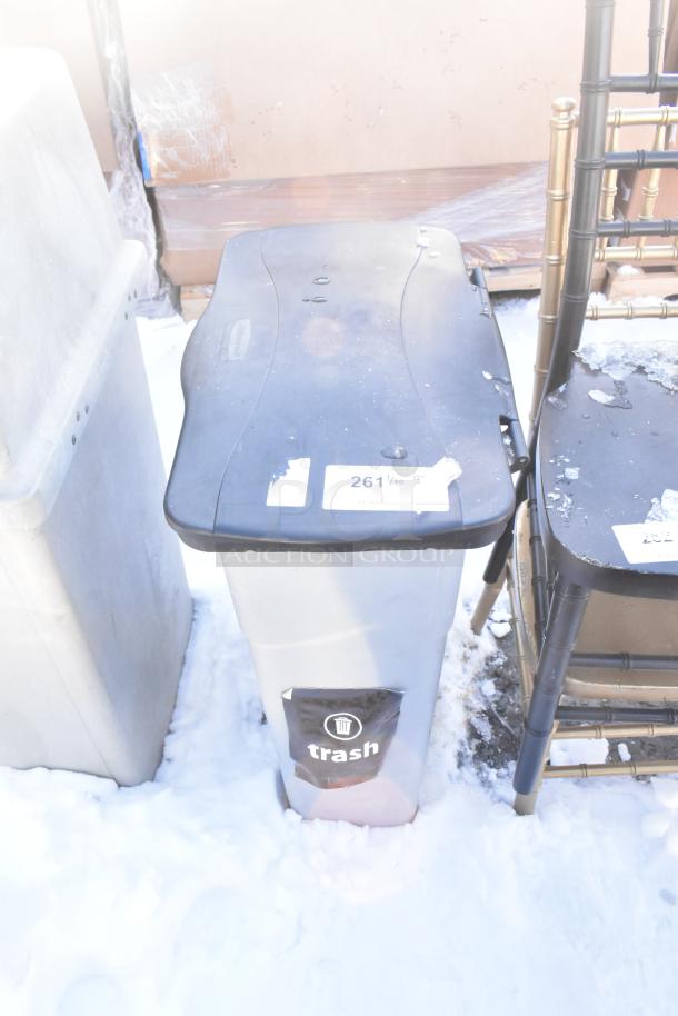 Black and gray Poly Trash Can with lid. Stickers on lid and front. Moderate wear and marks. Suitable for outdoor use.