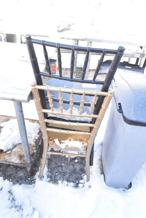 Two Chiavari stackable banquet chairs, one black and one gold, in snowy outdoor setting, visible wear.