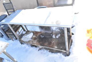 Stainless steel table with metal under shelf, commercial can opener mount; visible signs of outdoor exposure.