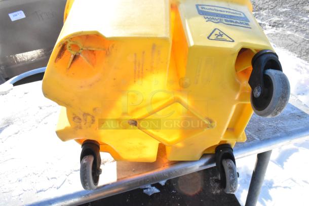 Rubbermaid yellow poly mop bucket with wringing attachment, visible wear, on commercial casters. Rubbermaid and WaveBrake labels.