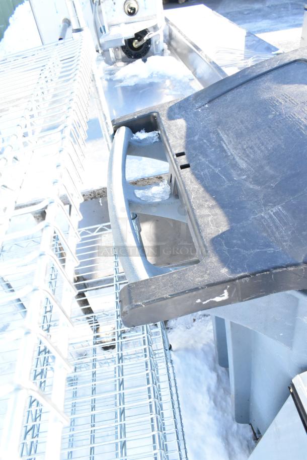 Poly trash can with lid and contents, including cutting boards, placed on metal racks. Moderate wear visible.