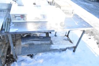 Stainless steel table with metal under shelf, scratches on the surface, in used condition, suitable for industrial use.