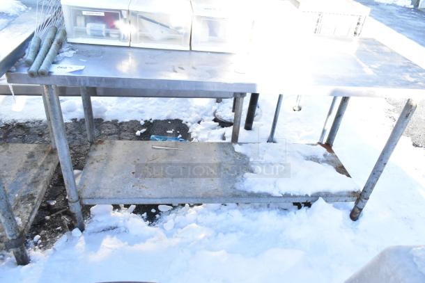 Stainless steel table with metal under shelf, showing wear. Ideal for industrial use, sturdy construction.