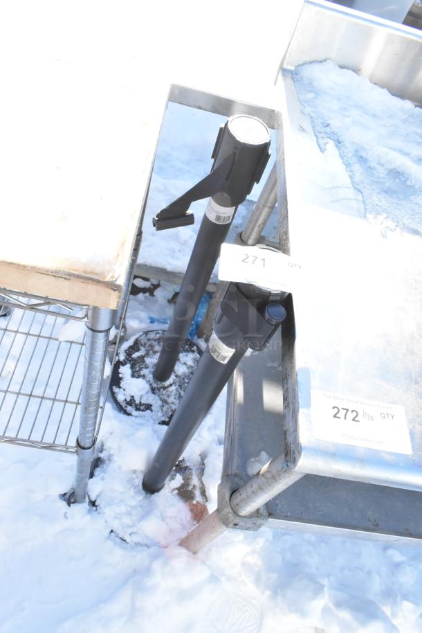 2 Winco CGS-38K stanchions with black posts and retractable belts, used condition, marked with auction tags "271" and "272".