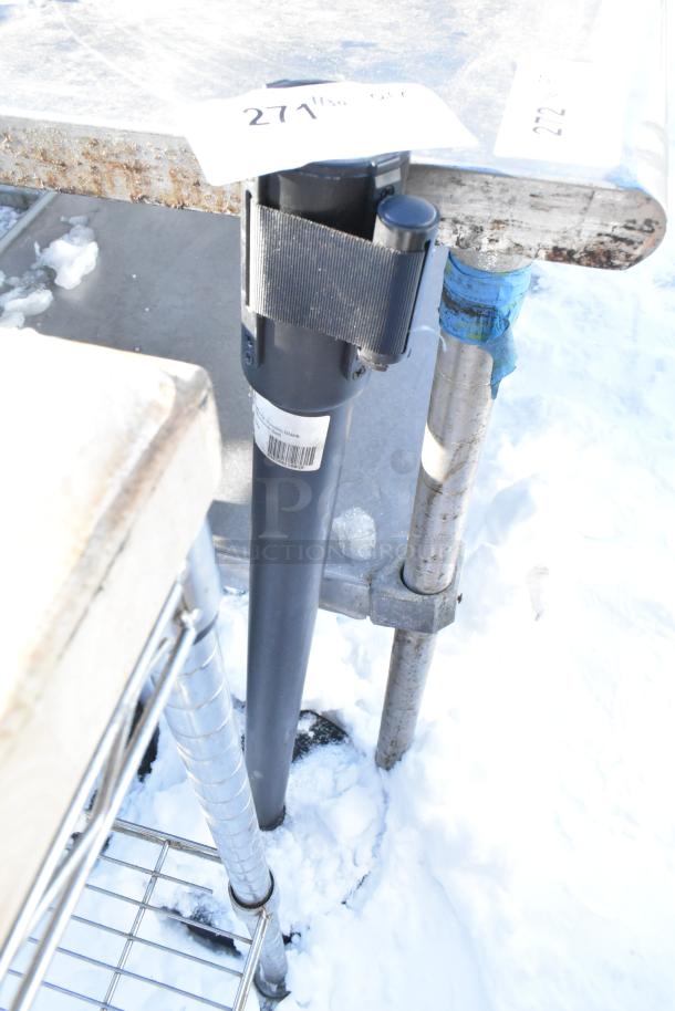 Two Winco CGS-38K stanchions in outdoor setting, black with attached black retractable straps. Good condition, metal posts.