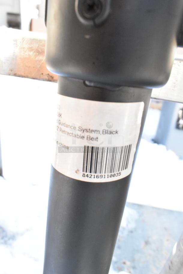 2 Winco CGS-38K stanchions, black, with retractable belts. Label shows barcode 842169110035. Good condition.