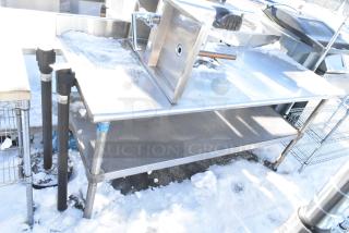 Stainless steel table with metal under shelf, featuring integrated sink and faucet. Good condition, ideal for commercial use.