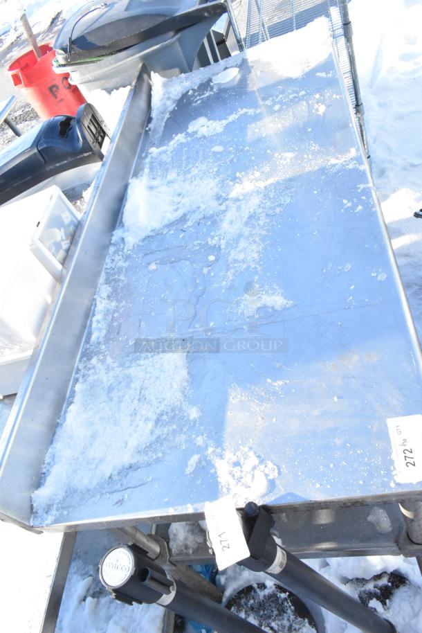 Stainless steel table with metal under shelf, snow-covered surface, tags indicating lot numbers 271 and 272.
