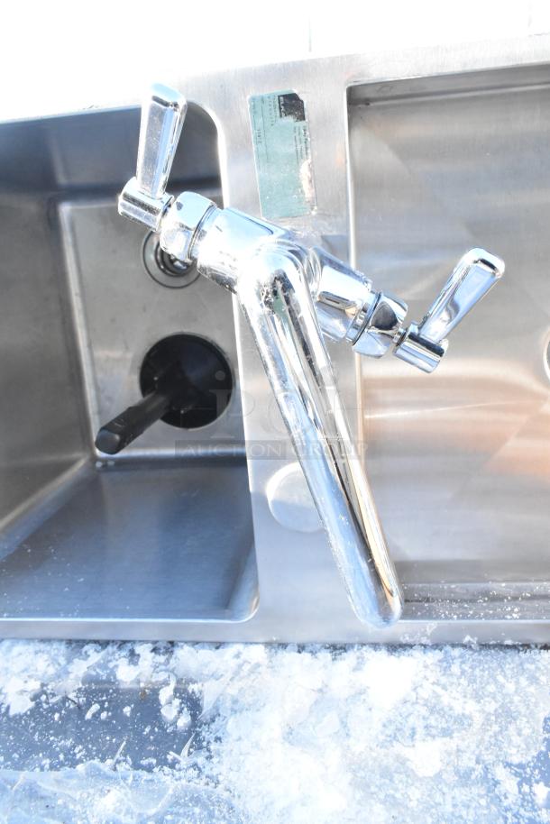 Stainless steel drop-in sink with a dual-handle chrome faucet, in good condition. Visible markings indicate model and specifications.